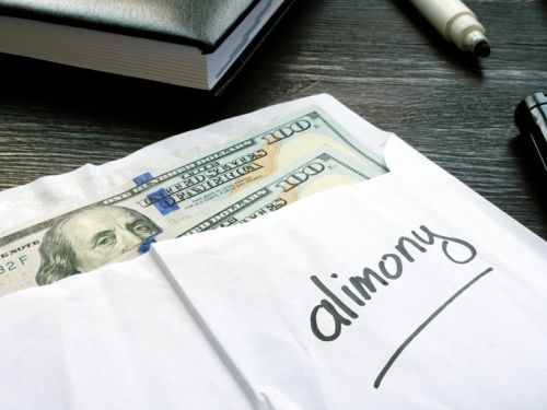 Alimony concept. Open envelope with cash on the wooden desk.